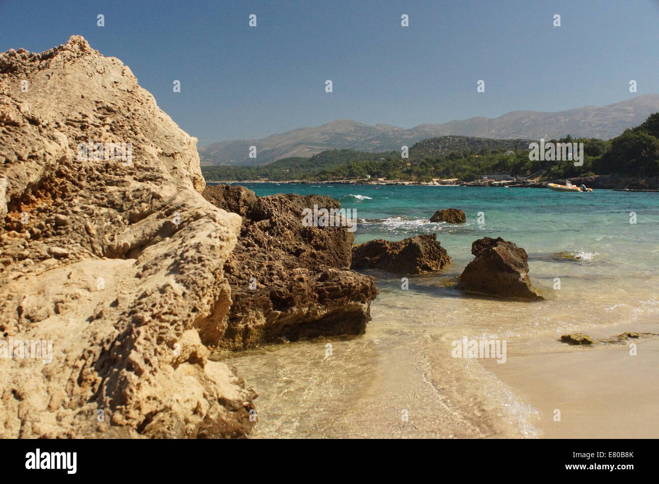 Scène de plage côtière, rochers, mer bleu clair, sable blanc, des montagnes, de l'eau Banque D'Images