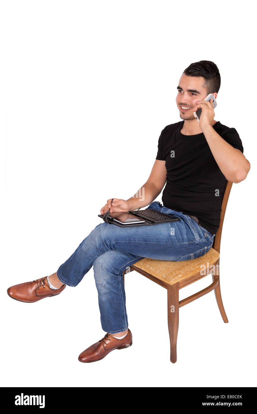 Jeune homme assis sur une chaise en regardant une tablette sur un fond blanc Banque D'Images