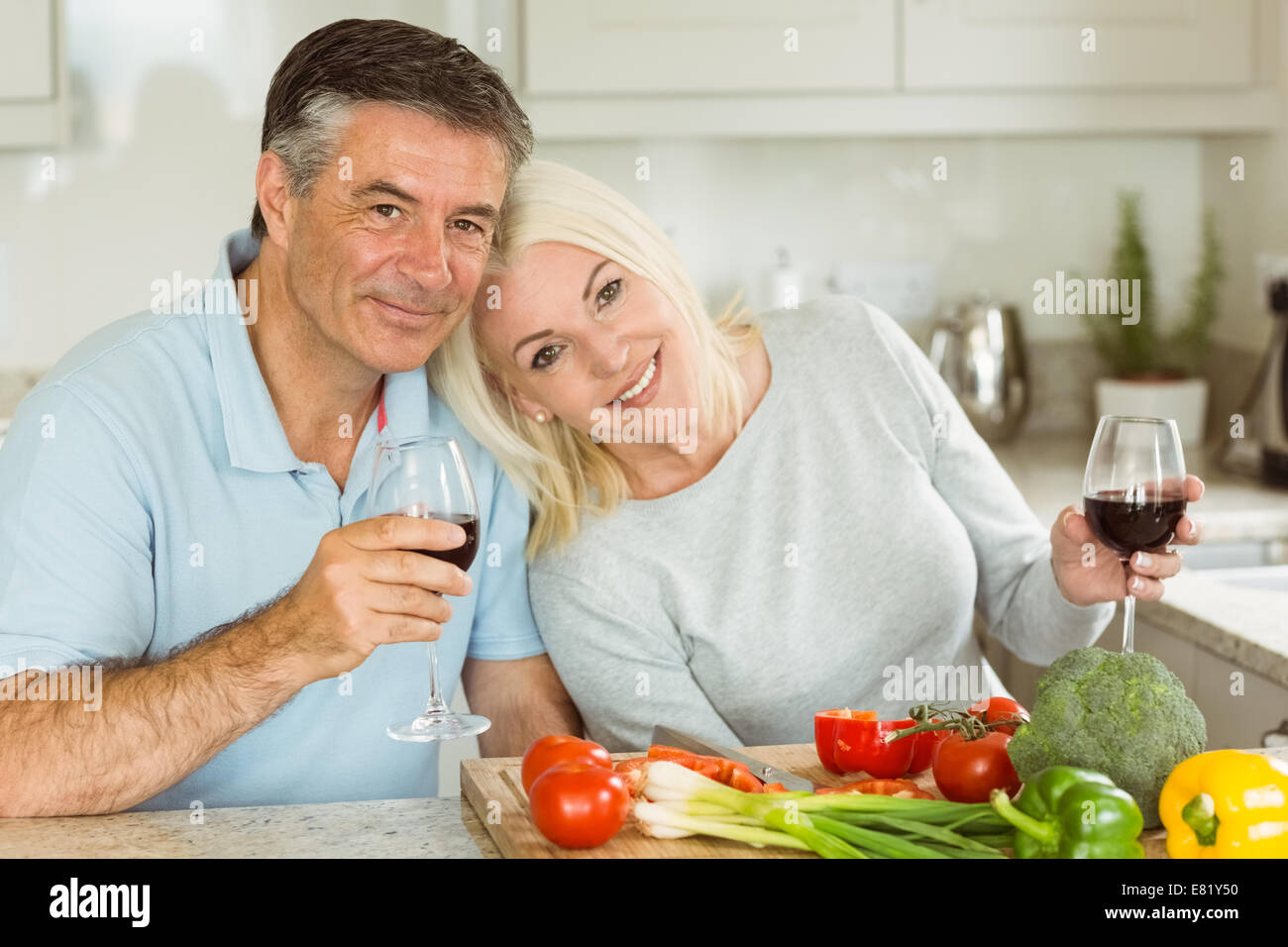 Couple ayant le vin rouge tout en faisant le dîner Banque D'Images