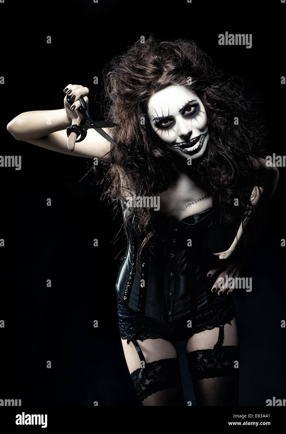 Jeune femme à l'image d'un gothique mal freak clown avec des ciseaux dans la main Banque D'Images