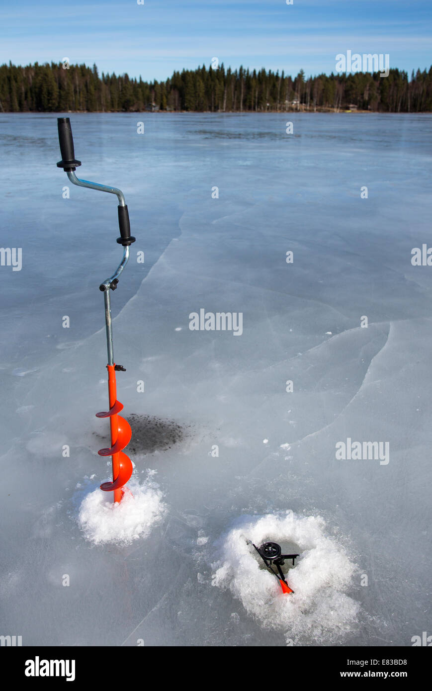 Mangeoire à glace à main isolée et canne de pêche à glace à pointe vers le haut au lac gelé à Winter, Finlande Banque D'Images