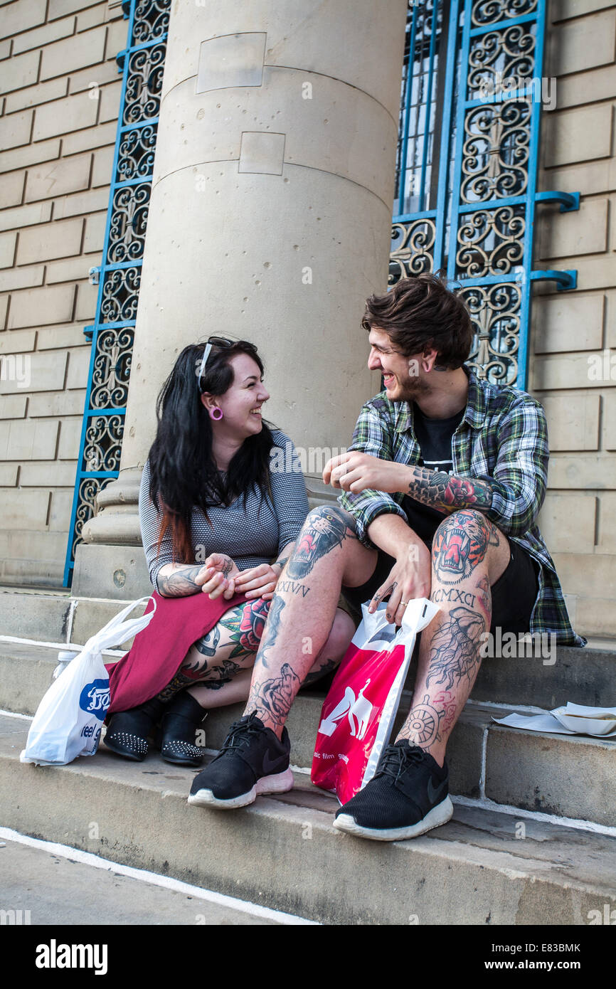 Un jeune couple avec des tatouages s'asseoir sur les marches à l'Hôtel de ville du centre-ville de Sheffield, UK Banque D'Images