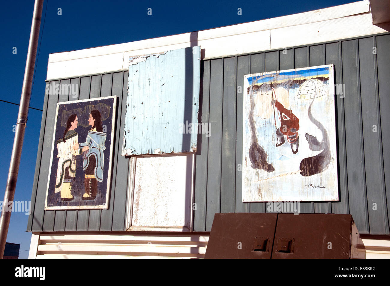 La façade de Pond Inlet's Art College affiche des peintures altérées de la culture locale--chant guttural, gauche, et de la chasse Banque D'Images