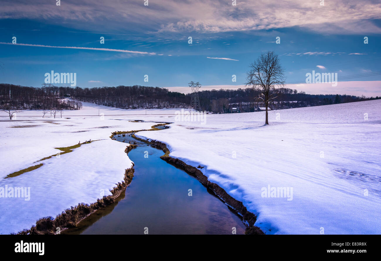 Petit cours d'eau à travers un champ couvert de neige dans les régions rurales de Carroll County, Maryland. Banque D'Images