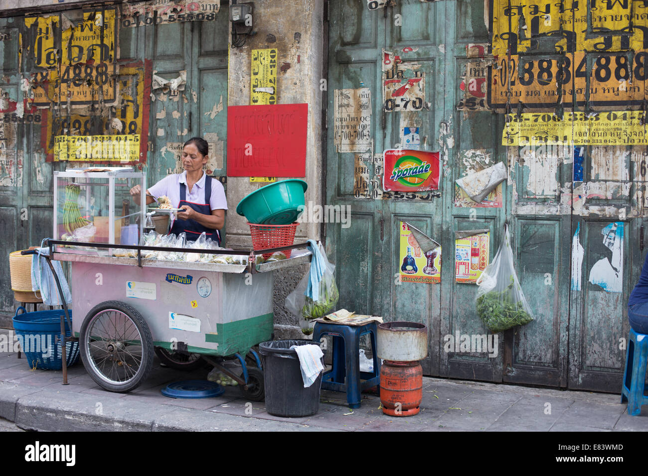 Food femelle porteur de préparer des aliments contre un mur vert, Chinatown, Bangkok, Thaïlande. Banque D'Images