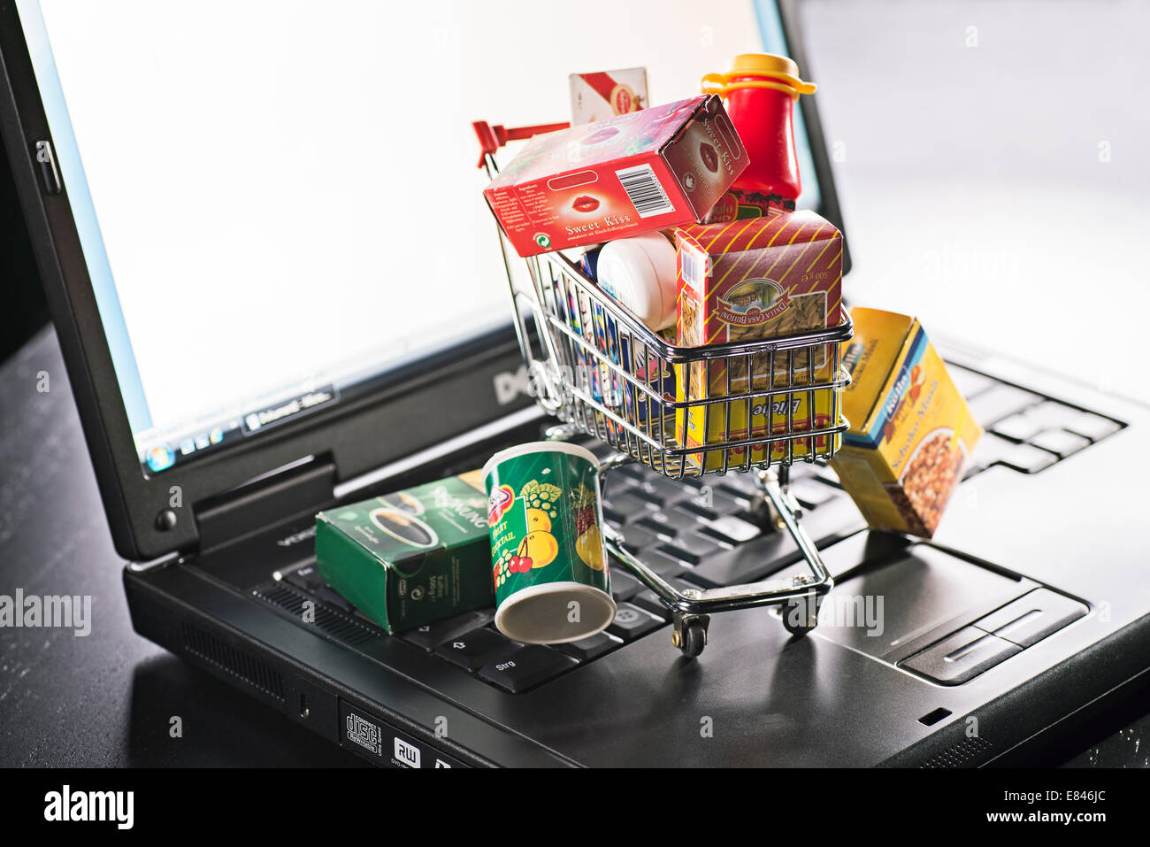 Panier miniature avec l'emballage alimentaire et ordinateur portable comme un symbole pour le magasinage en ligne. Banque D'Images