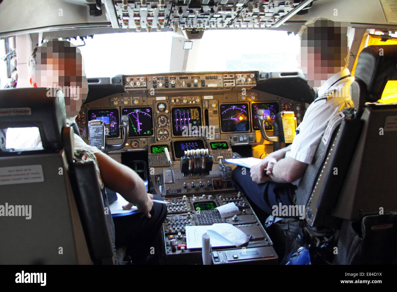 Un pilote et copilote (faces pixelisées) aux commandes dans le cockpit d'un Boeing 747 jumbo jet sur le terrain à Heathrow Banque D'Images