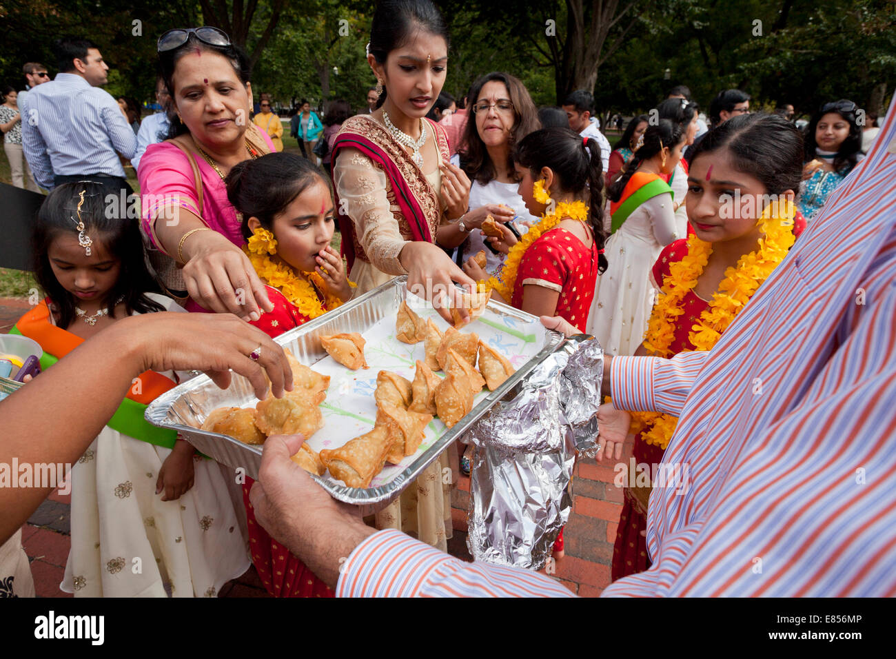 Foule rassemblée autour d'une assiette de samosas Indiens Banque D'Images