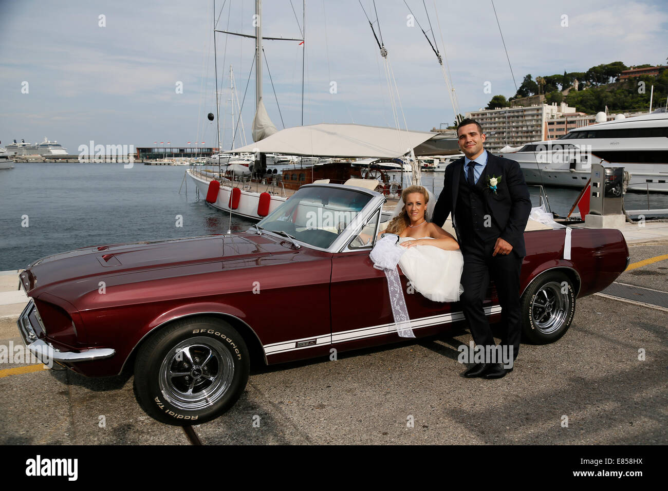 Mariée et le marié qui posent avec une Ford Mustang décapotable dans un port de voiture Banque D'Images