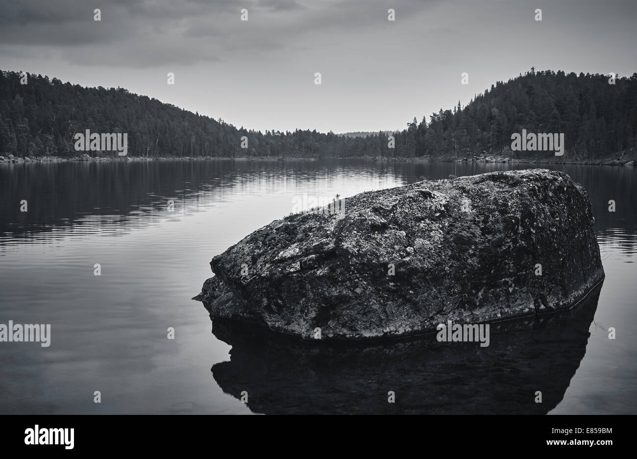 Grande pierre dans le lac, ciel nuageux et journée calme, image en noir et blanc teinté Banque D'Images