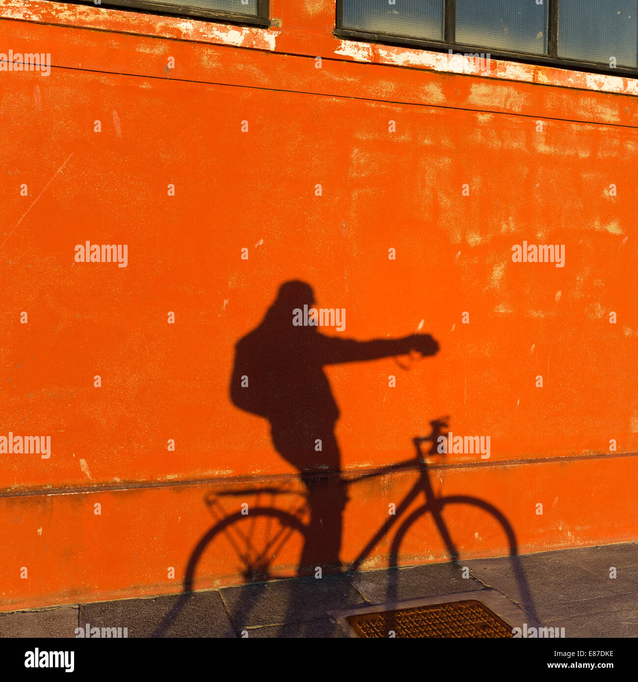Self Portrait : l'ombre d'un homme sur un vélo sur un mur rouge comme il lui-même, les photographies selfies soirée d'UK Banque D'Images