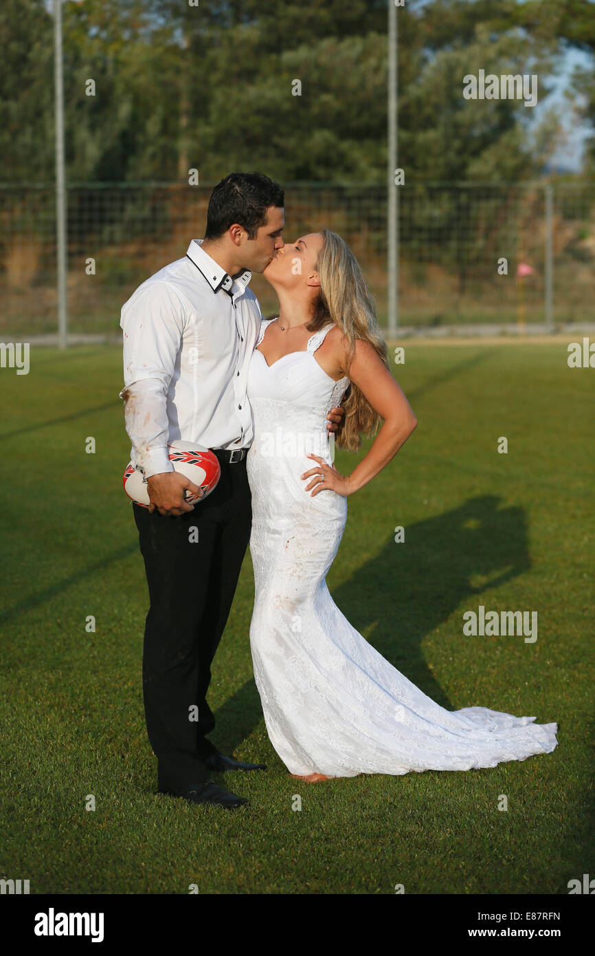 Corbeille la robe, mariée et le marié s'embrasser sur un terrain de rugby Banque D'Images