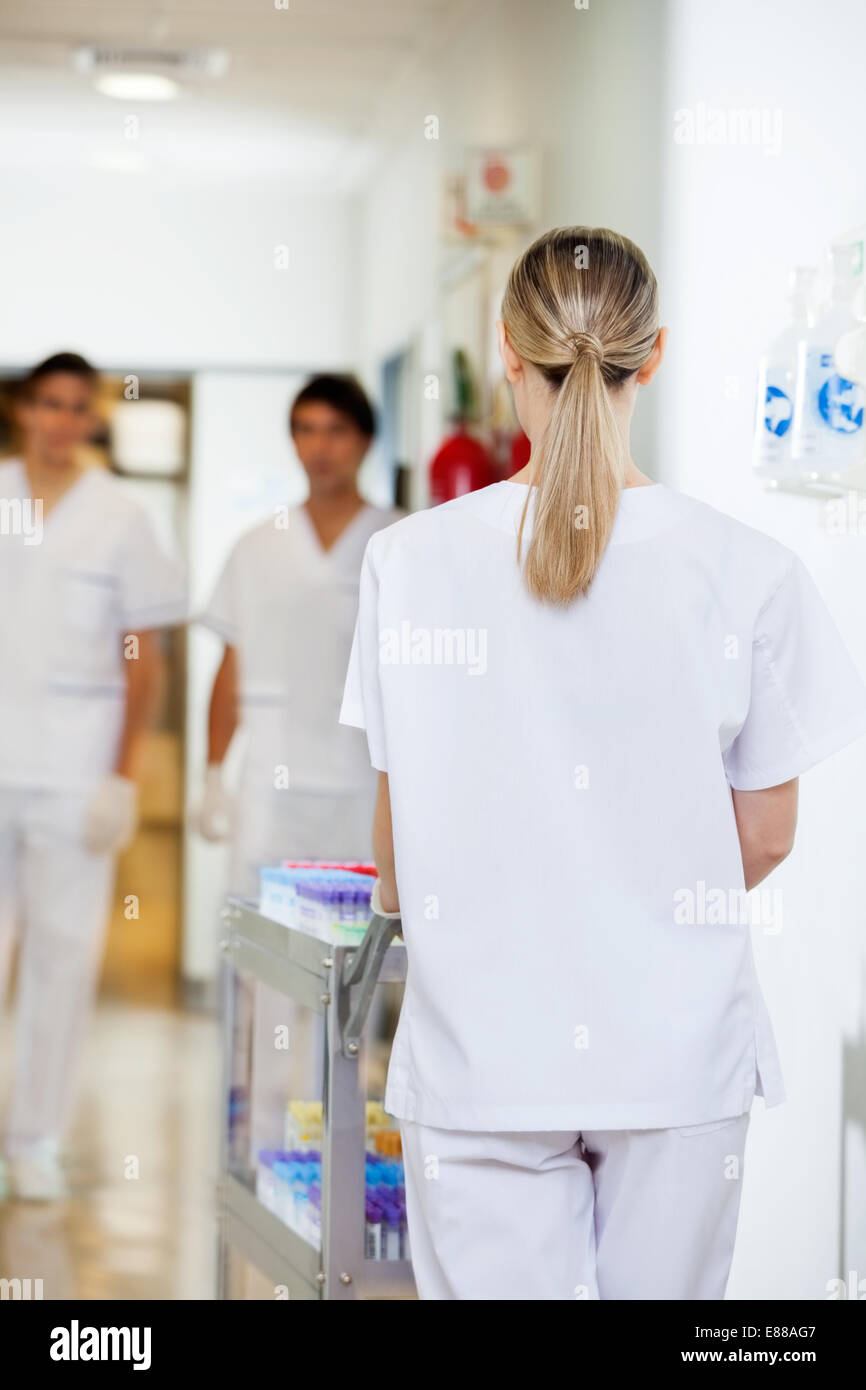 Poussant technicien medical cart in hospital hallway Banque D'Images