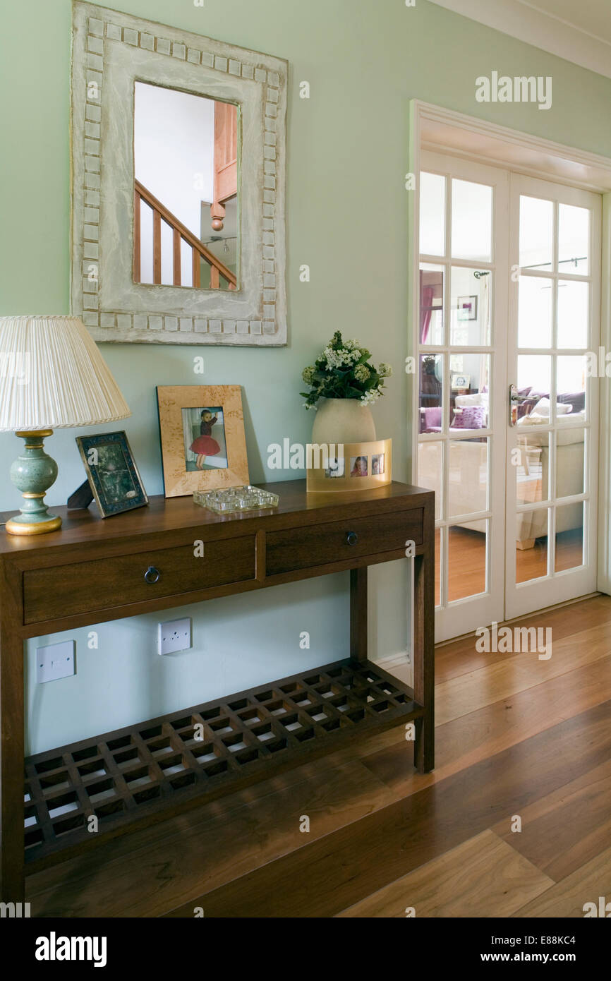 Miroir encadré blanc au-dessus de table console en pastel green country hall avec salon de portes vitrées Banque D'Images