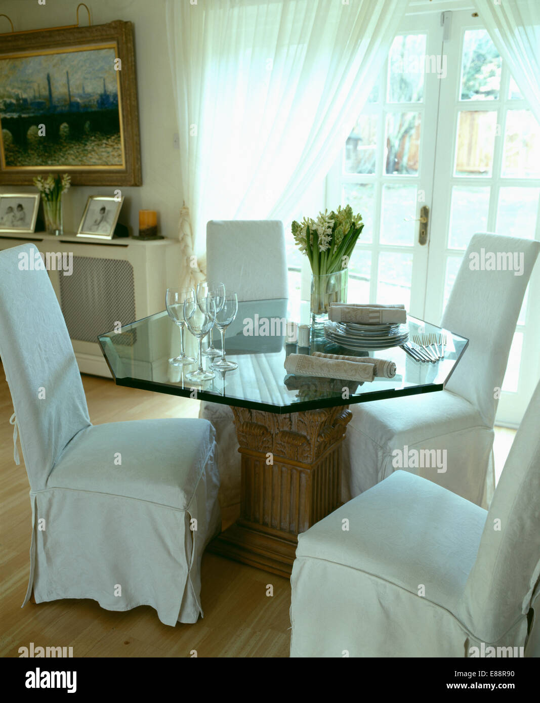Meuble blanc-couvre sur les fauteuils et table en verre hexagonal en salle à manger convertie de garage Banque D'Images