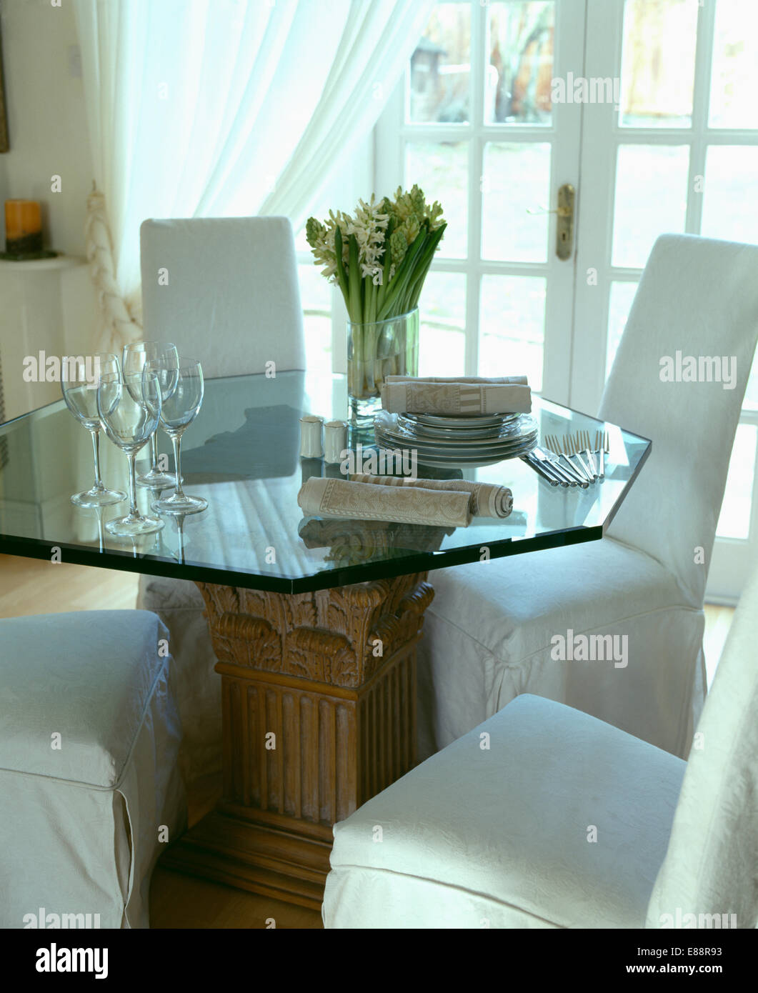 Meuble blanc-couvre sur les fauteuils et table en verre hexagonal en salle à manger convertie de garage Banque D'Images
