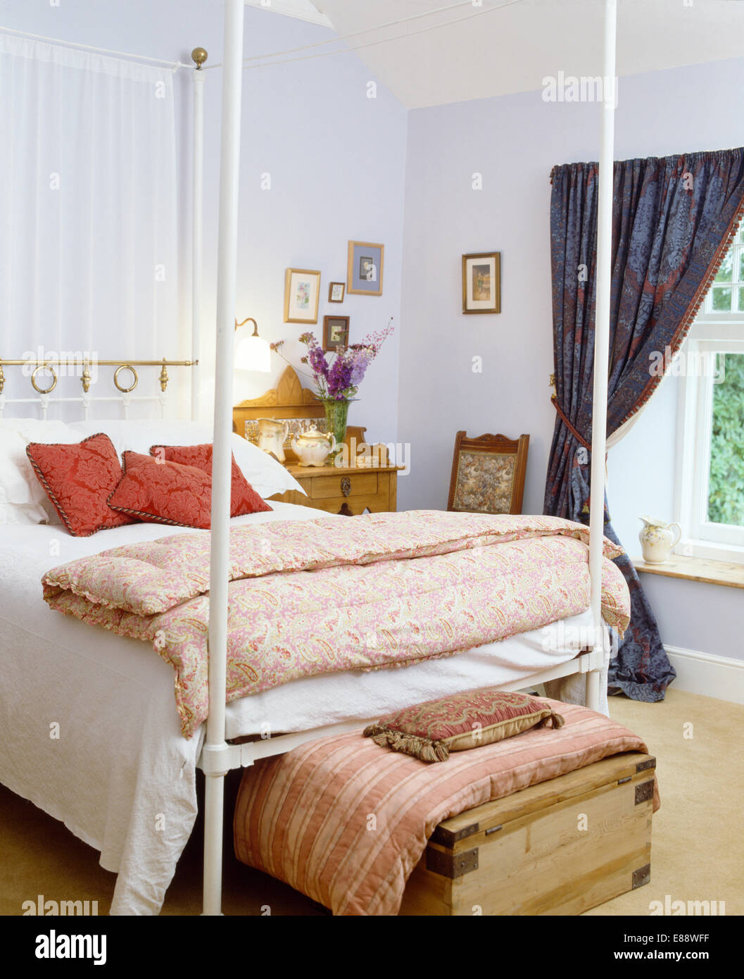 Édredon vintage pliée sur lit de métal blanc en bleu pâle avec coussins sur  old pine poitrine au pied du lit Photo Stock - Alamy