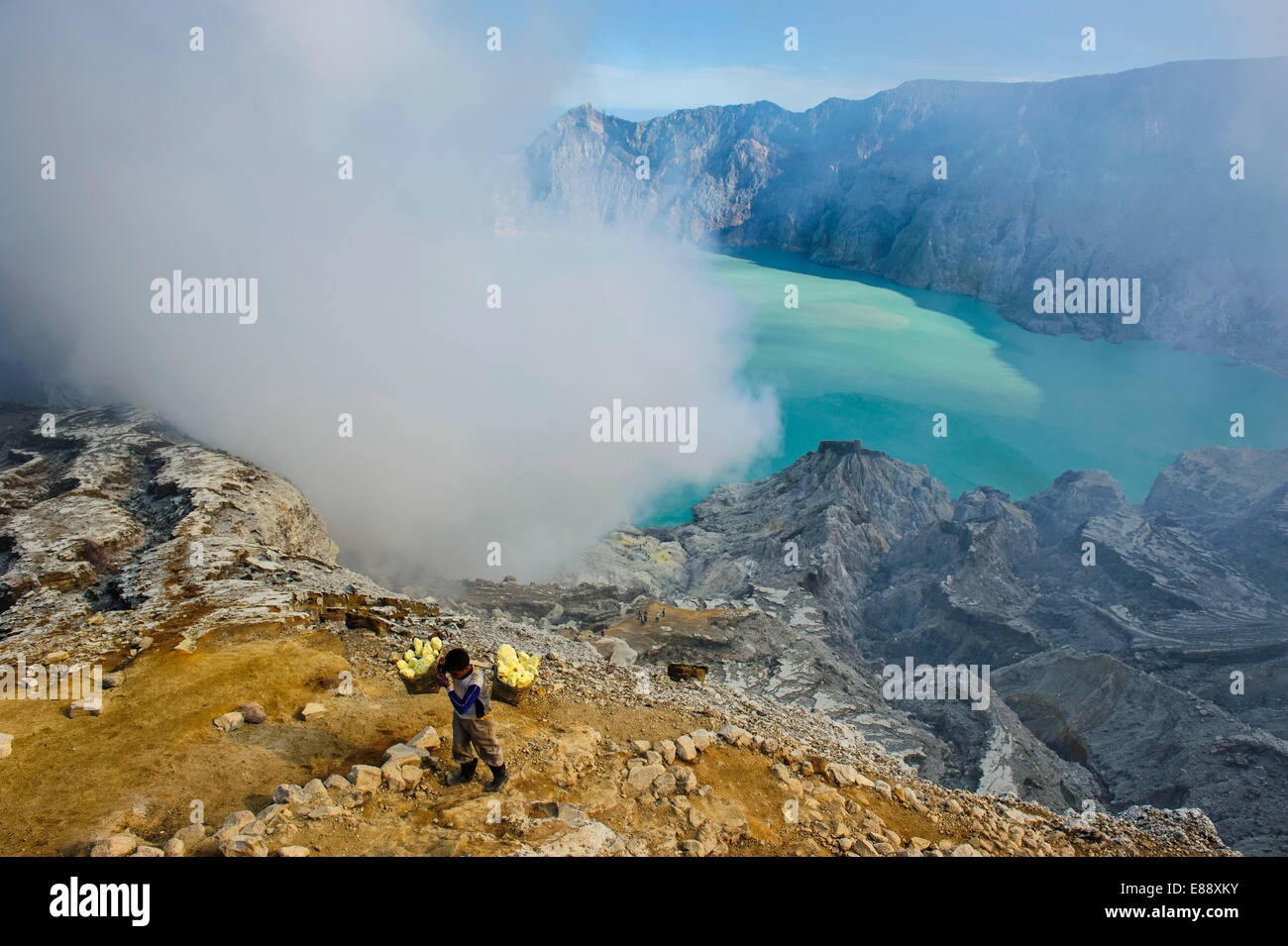 Travailleur chargé avec de gros morceaux de soufre dans les nuages de vapeur avant sur le lac de cratère Ijen, Java, Indonésie, Asie du Sud, Asie Banque D'Images