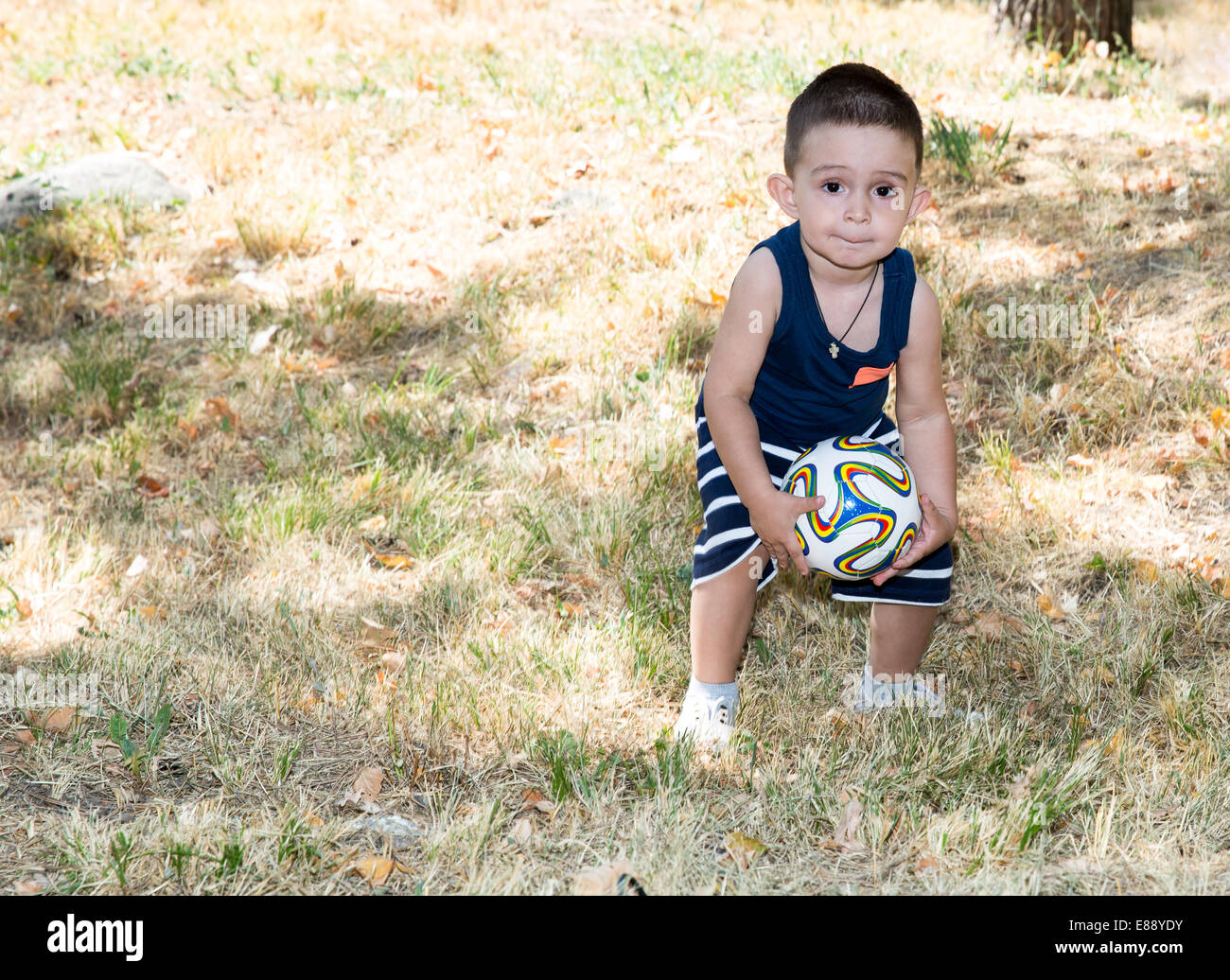 Adorable petit enfant garçon avec ballon de soccer dans le parc de la nature à l'été. L'utiliser pour bébé, éducation ou le sport concept Banque D'Images
