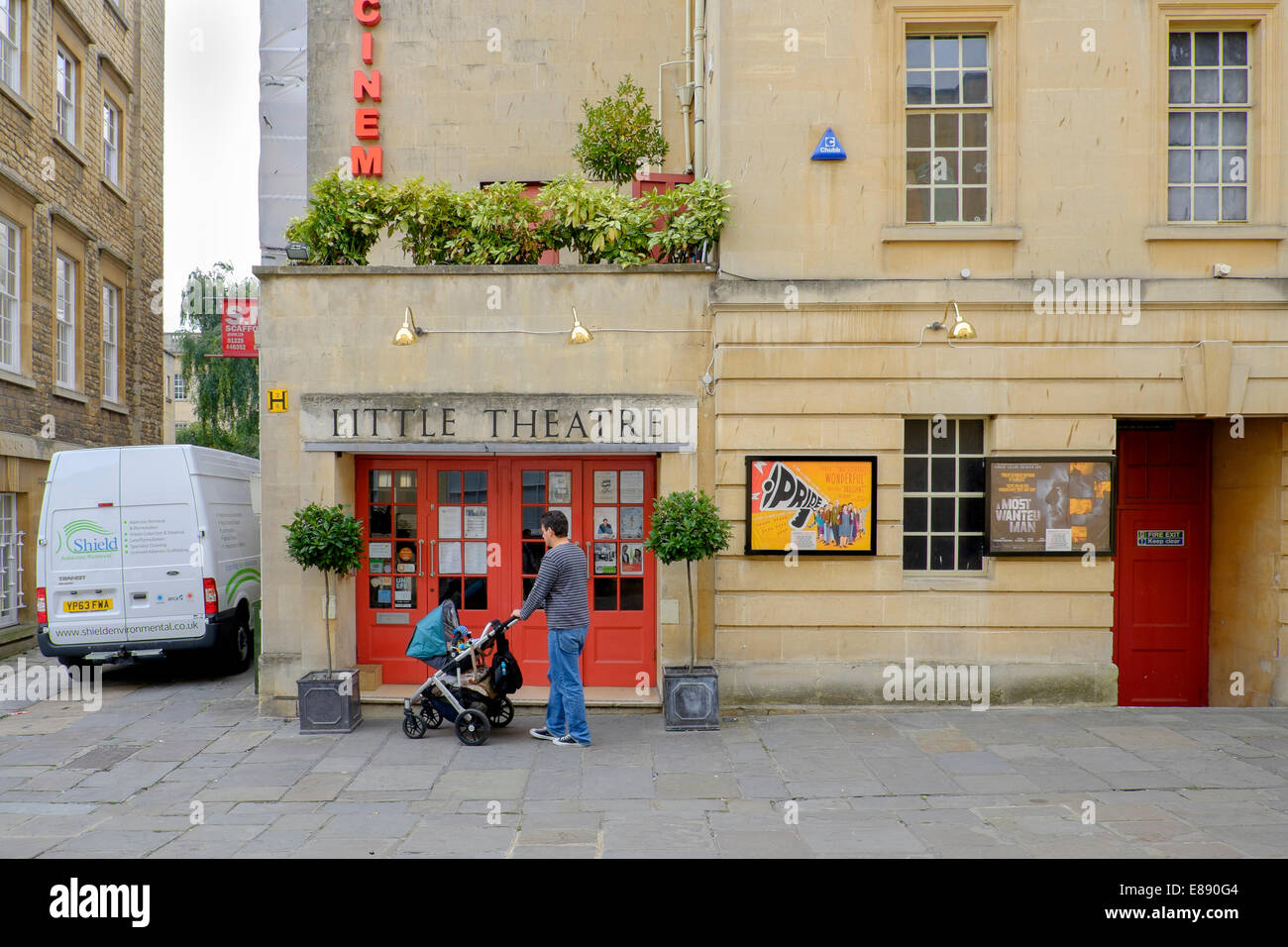 Un homme poussant un landau attend à l'extérieur du petit théâtre cinema à Bath, Somerset, Angleterre, Royaume-Uni Banque D'Images
