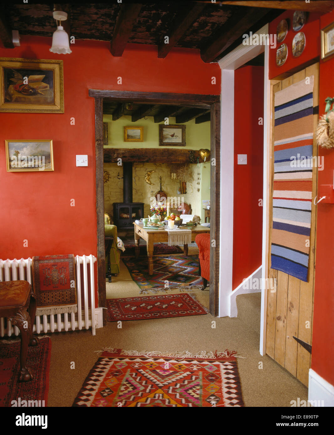 Tapis Kelim sur plancher et tapis à rayures sur porte de red cottage hall avec porte ouverte à la salle de séjour Banque D'Images