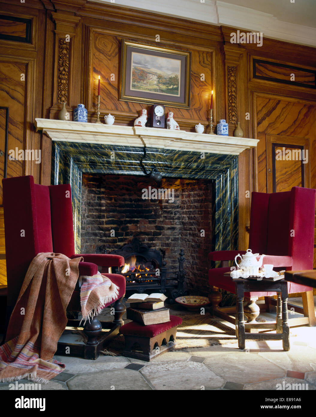 Red Velvet wingchairs de chaque côté de la cheminée de marbre en pays salon avec murs en lambris Banque D'Images