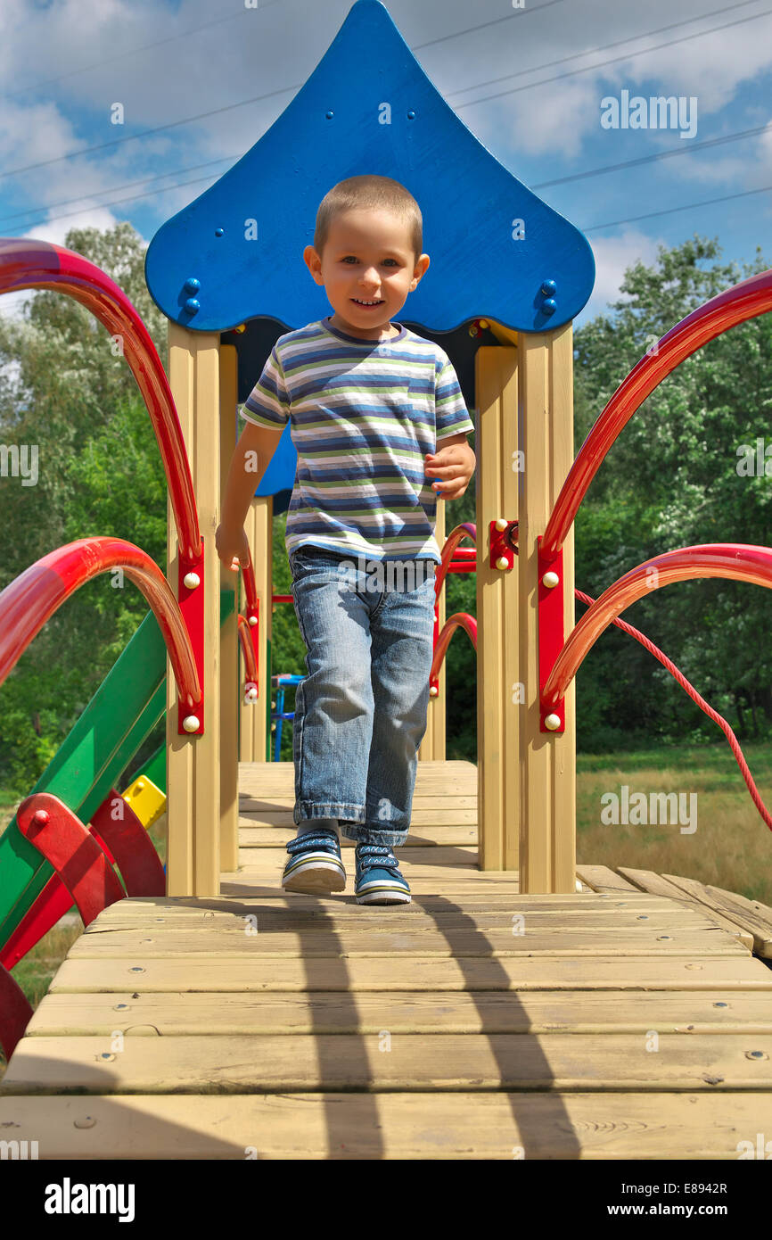 Petit garçon en jeans et t-shirt jouant sur l'aire de jeux Photo Stock -  Alamy