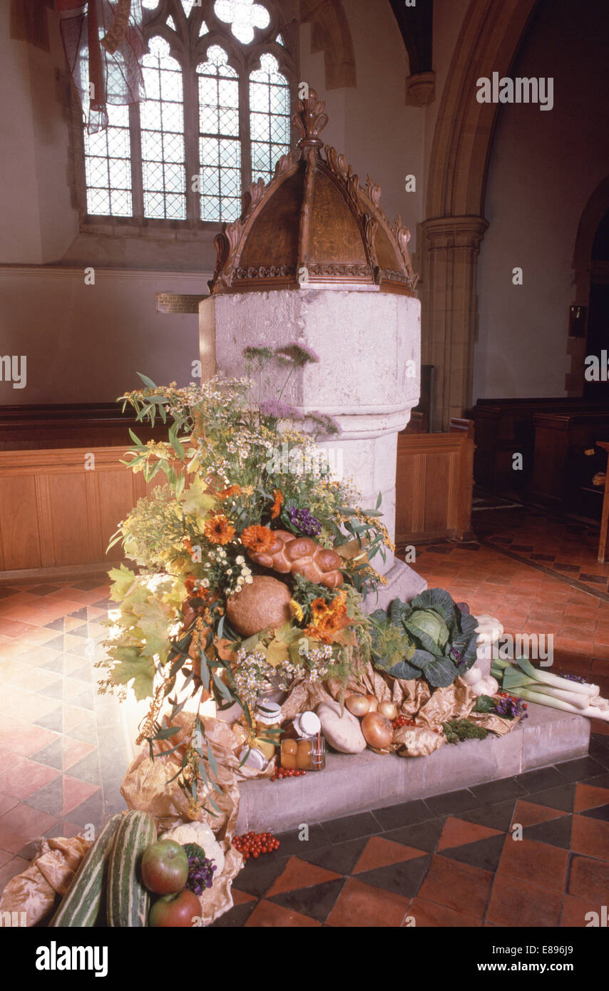 Affichage de la récolte de légumes et de fleurs d'automne sur la pierre font dans la vieille église de campagne Banque D'Images