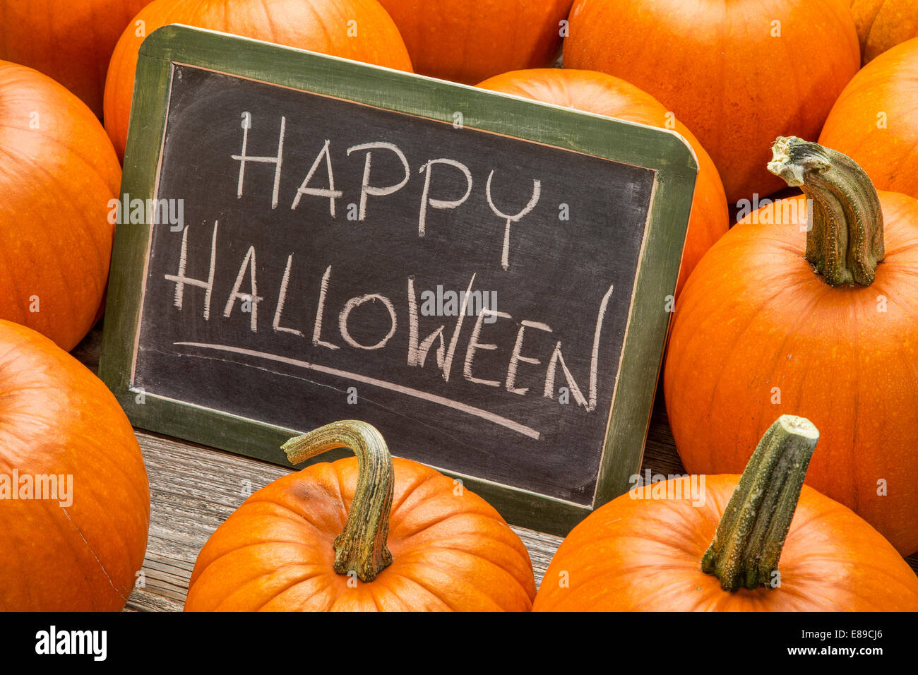 Happy Halloween - écriture à la craie blanche sur un tableau noir ardoise vintage entouré de citrouilles Banque D'Images