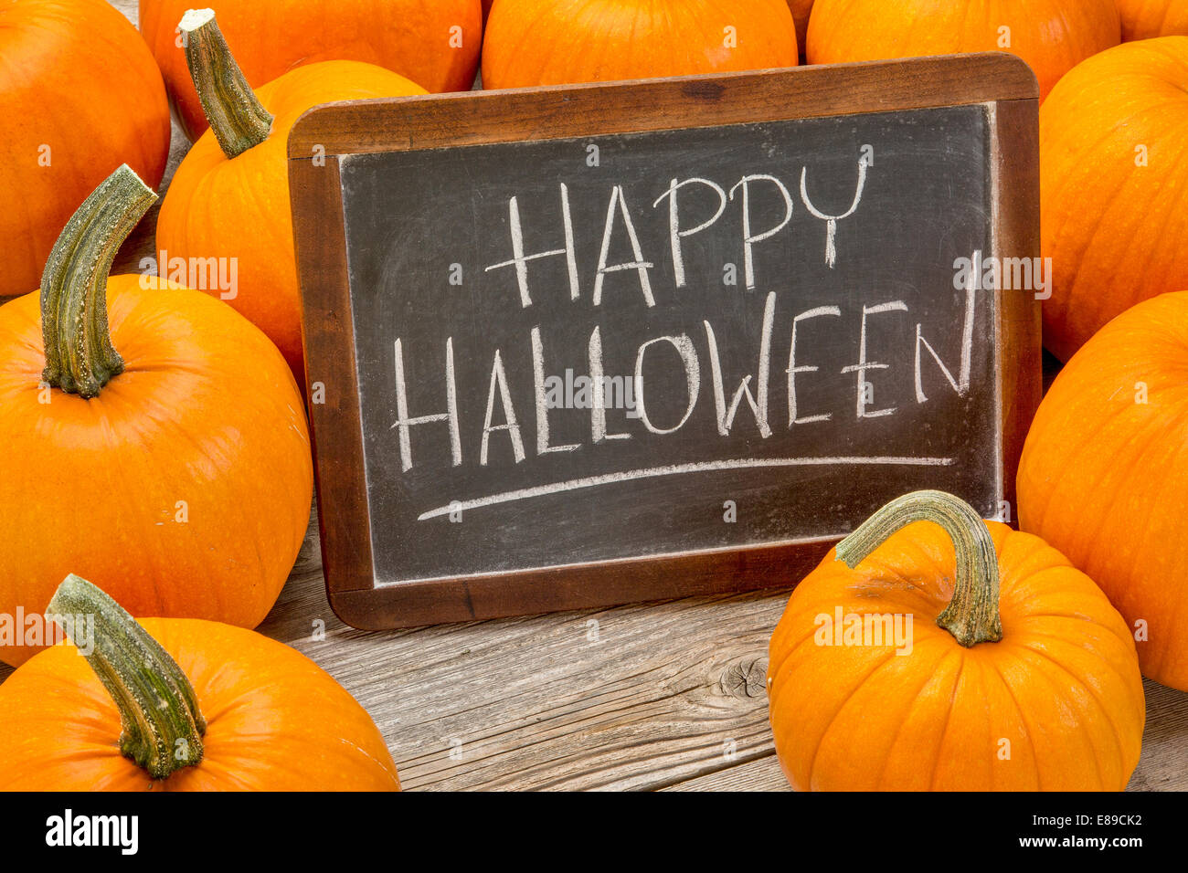 Happy Halloween - écriture à la craie blanche sur un tableau noir ardoise vintage entouré de citrouilles Banque D'Images