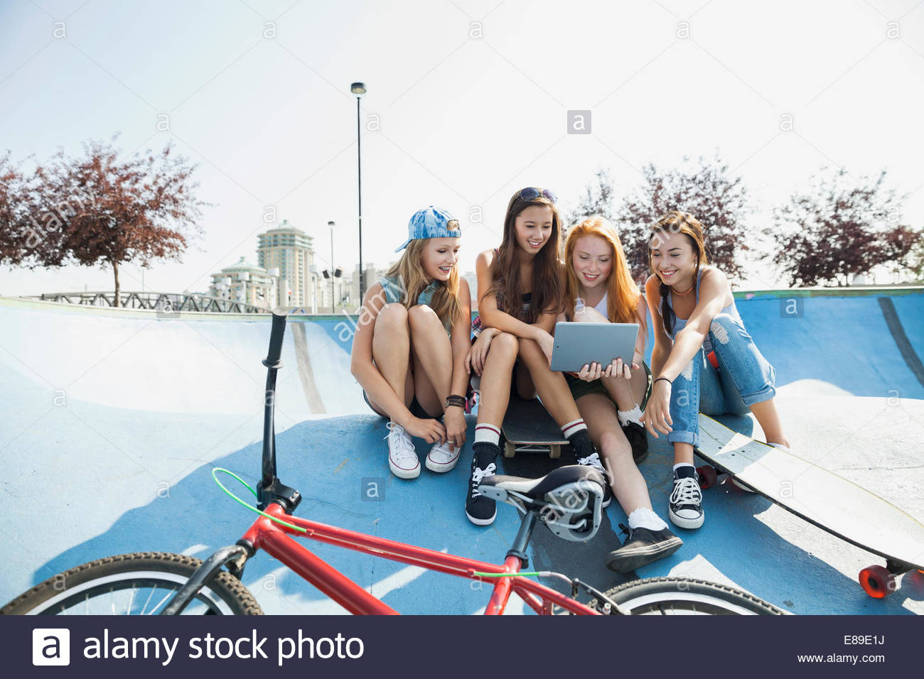 Teenage Girls using digital tablet at parc de planche à roulettes Banque D'Images