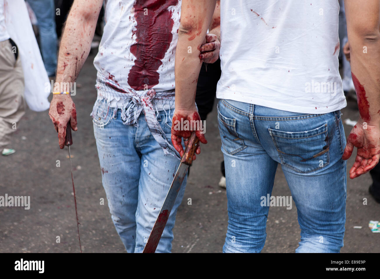 Les hommes musulmans chiites, couverts dans leur propre sang, transportant des couteaux, dans les rues de Nabatieh, Liban, au cours de la journée d'Ashoura. Banque D'Images