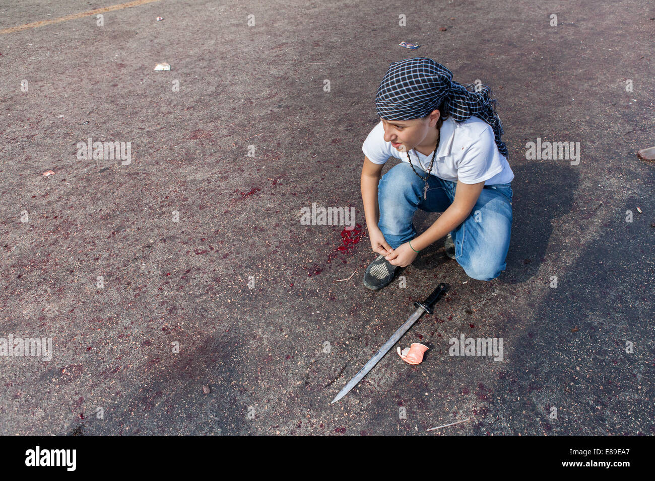 Un jeune garçon musulman chiite avec une épée, les traverses ses lacets sur une sanglante street, au cours de la journée d'Ashoura à Nabatieh, Liban. Banque D'Images