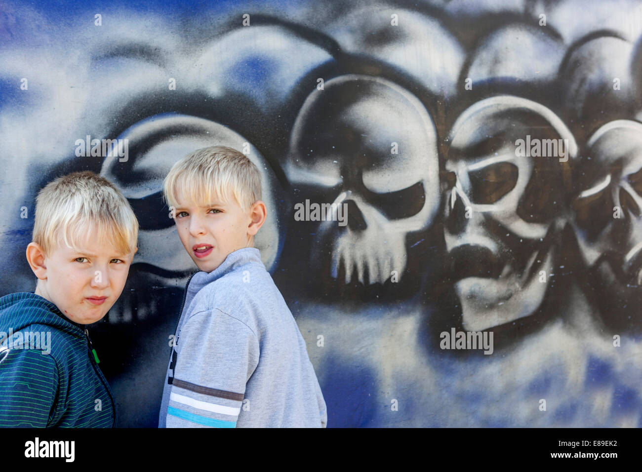 deux garçons devant un mur avec des crânes peints street art enfant Banque D'Images