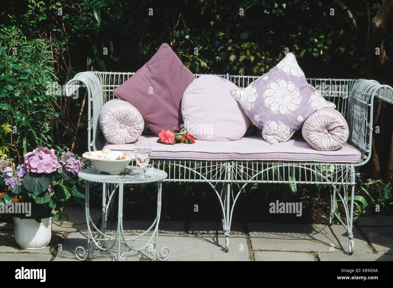 Mauve vérifié et coussins fleurs blanc wirework sur banc de jardin sur terrasse d Banque D'Images