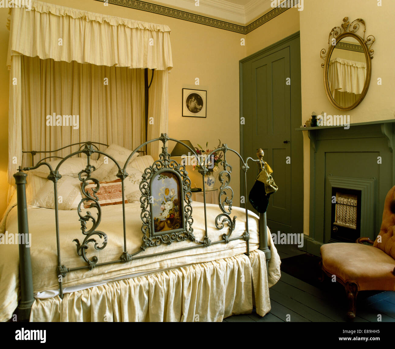 Rideaux crème ornée de meubles anciens peints sur, dais lit dans chambre  avec cheminée au gaz et cheminée peinte verte Photo Stock - Alamy