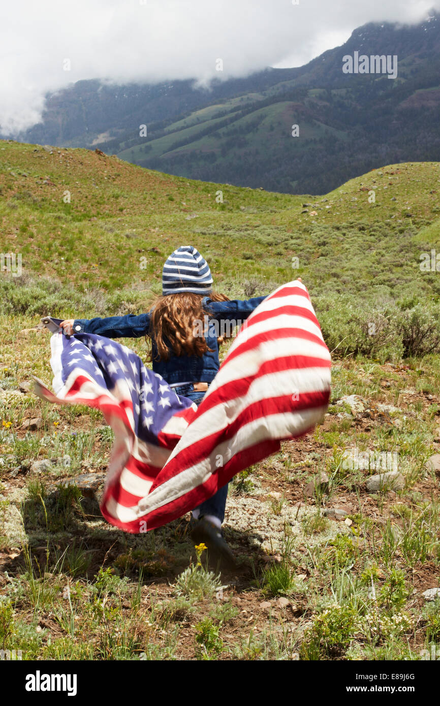 Girl wrapped in American Flag in field Banque D'Images