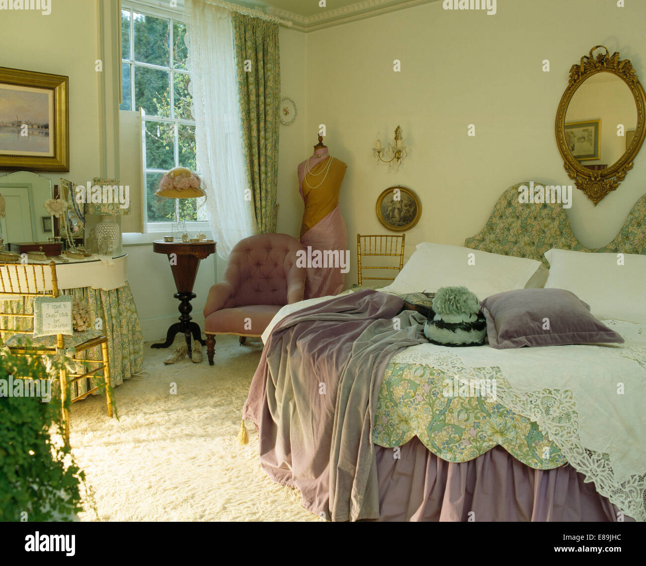 Jet mauve sur lit avec couette vert pâle et couvre-lit en dentelle en pays chambre avec fauteuil rose Banque D'Images