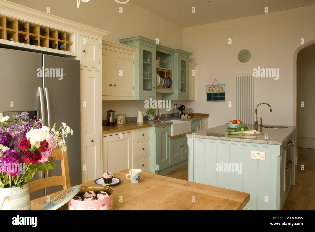 L'unité de l'île centrale turquoise pâle en pays cuisine avec vase de fleurs sur une table à manger d'été Banque D'Images