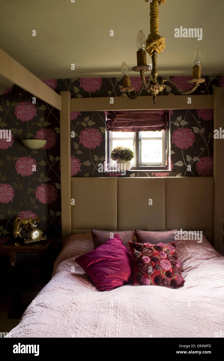 Coussins rose et mauve couvrir sur quatre colonnes avec tête de lit rembourrée en chambre cottage Banque D'Images