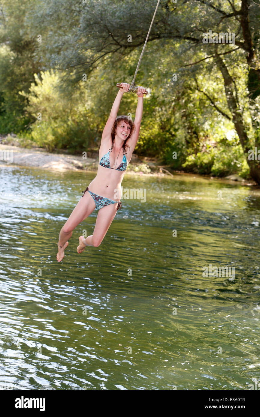 Femme sautant sur une corde dans l'eau, la rivière Birse, Suisse Banque D'Images