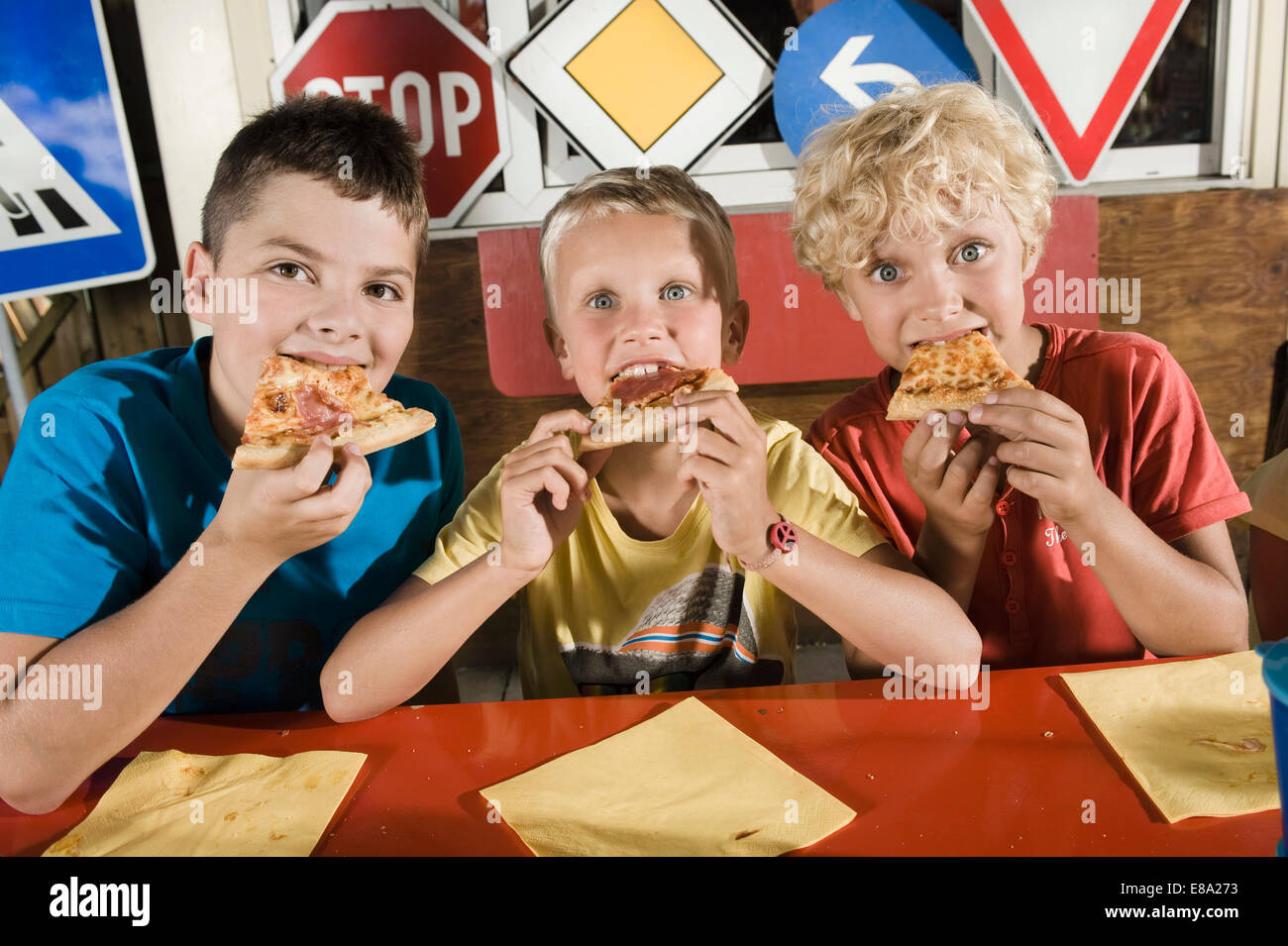 Trois garçons de manger une pizza à la zone d'entraînement de pilote Banque D'Images