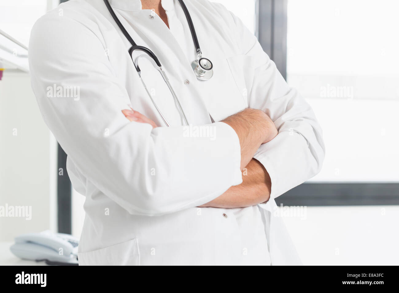 Doctor holding les bras croisés, mid section Banque D'Images