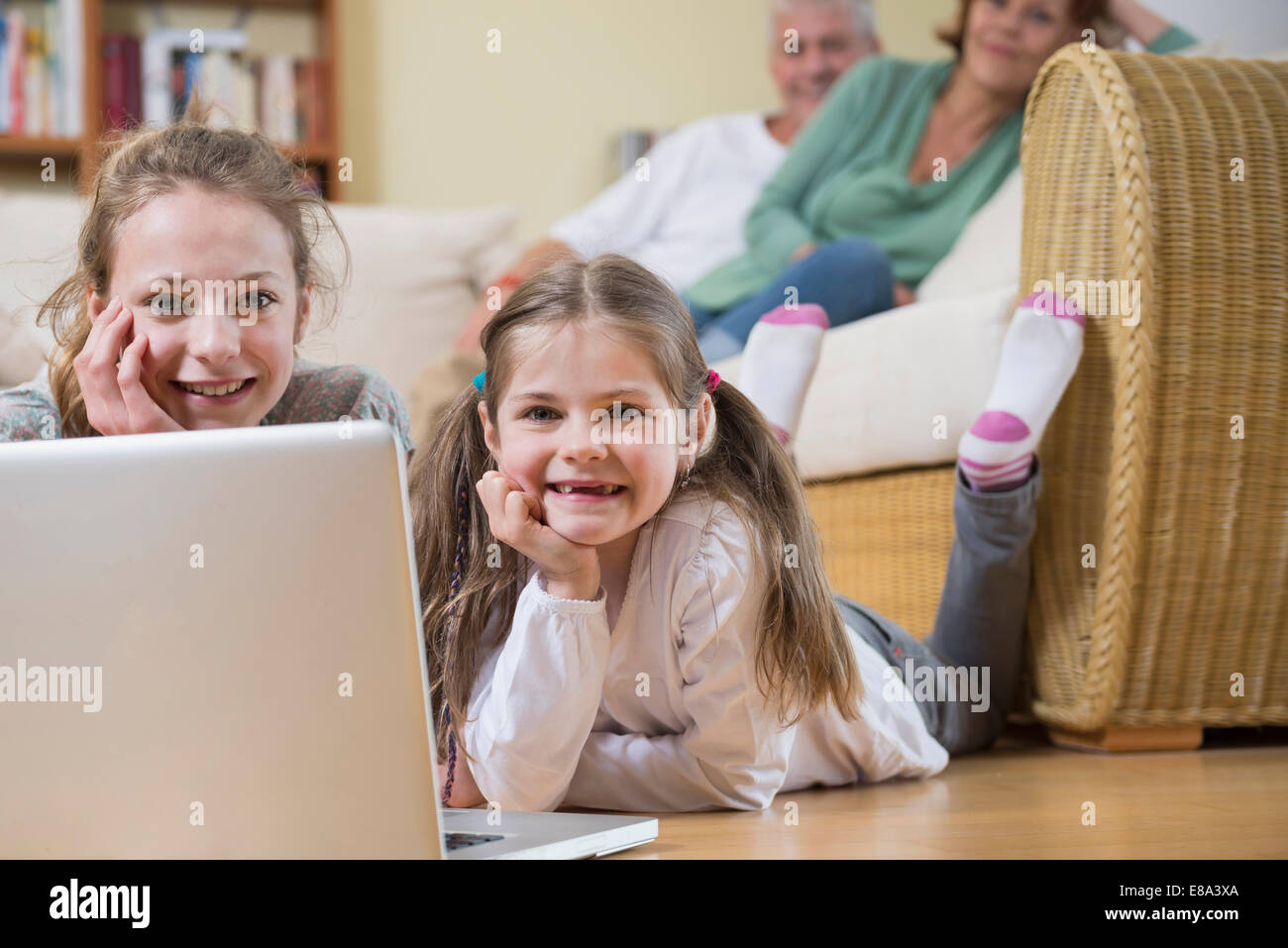 Petites-filles à l'aide d'ordinateur portable tandis que les grands-parents en arrière-plan Banque D'Images