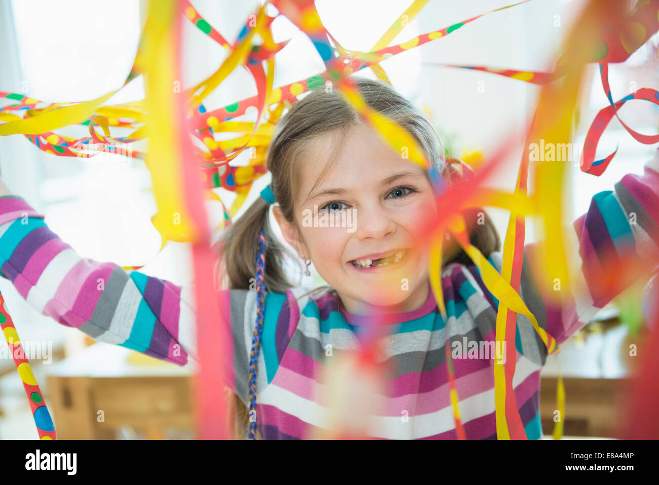 Portrait of Girl with blowout paper streamer at Birthday party, smiling Banque D'Images