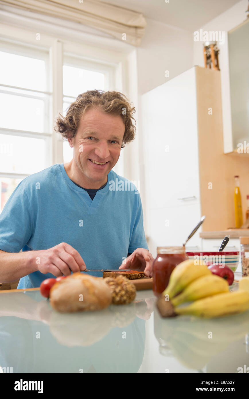 Smiling man sitting at table de petit déjeuner dans la cuisine Banque D'Images