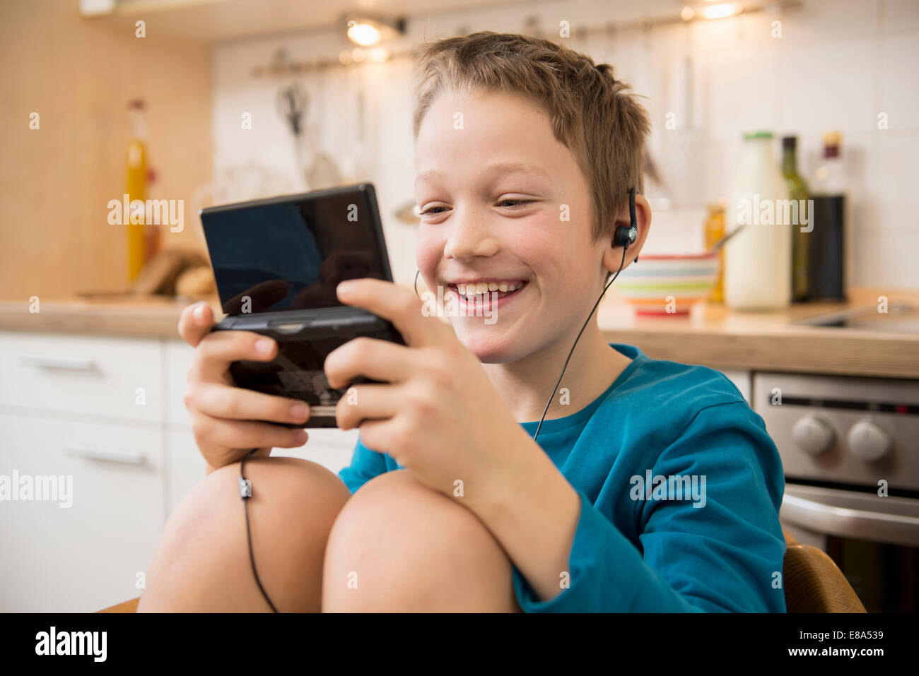 Boy playing video game in kitchen Banque D'Images Boy playing video game in kitchen Banque D'Images