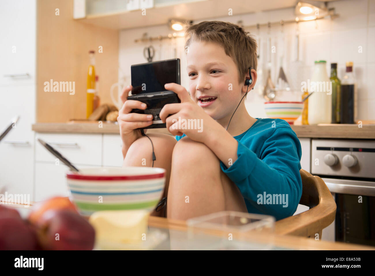 Boy playing video game in kitchen Banque D'Images Boy playing video game in kitchen Banque D'Images