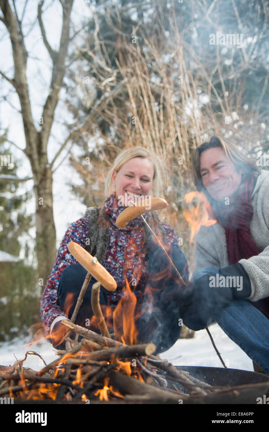 Saucisse barbecueing couple sur feu de camp, Bavière, Allemagne Banque D'Images