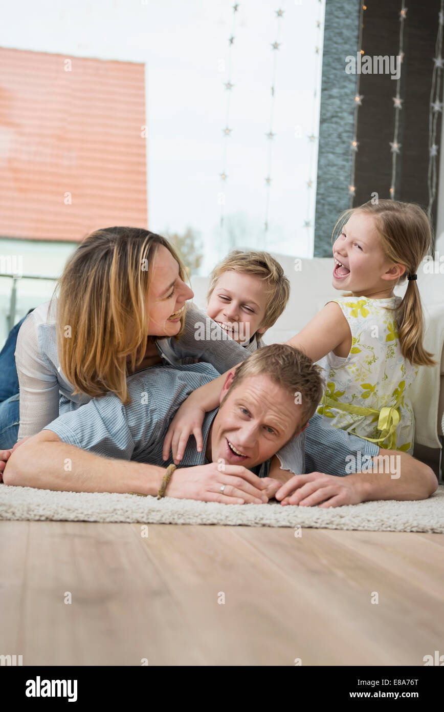 Famille heureuse avec deux enfants à la maison, couché sur le plancher Banque D'Images